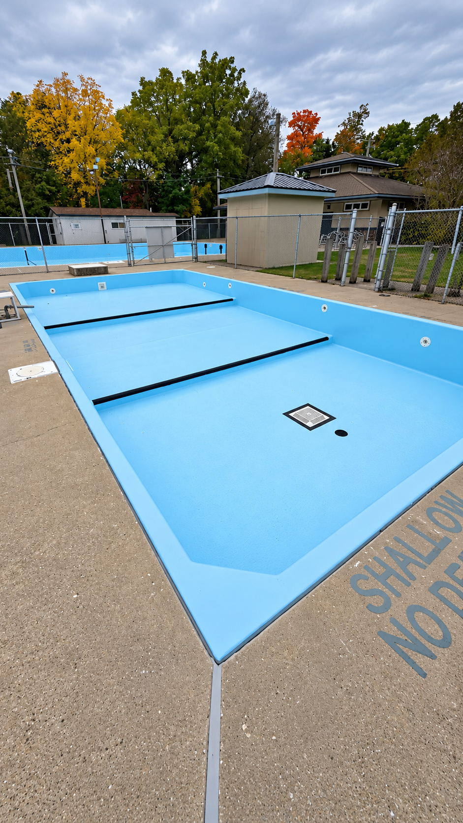Empty outdoor swimming pool with bright blue interior and surrounding deck