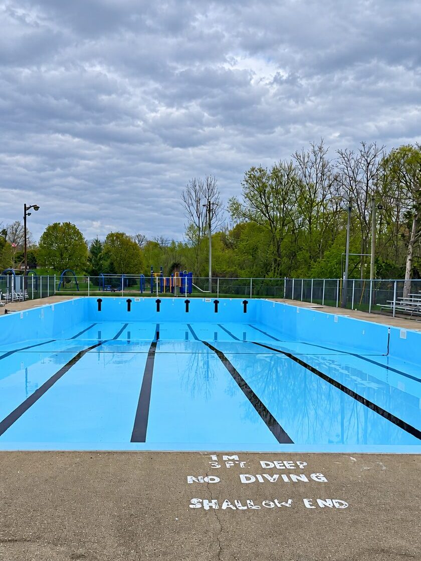 Empty outdoor swimming pool with lane markings and shallow-end safety lettering